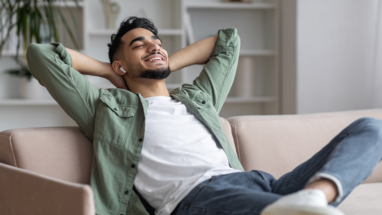 Image: Man sitting on couch listening to AirPods.