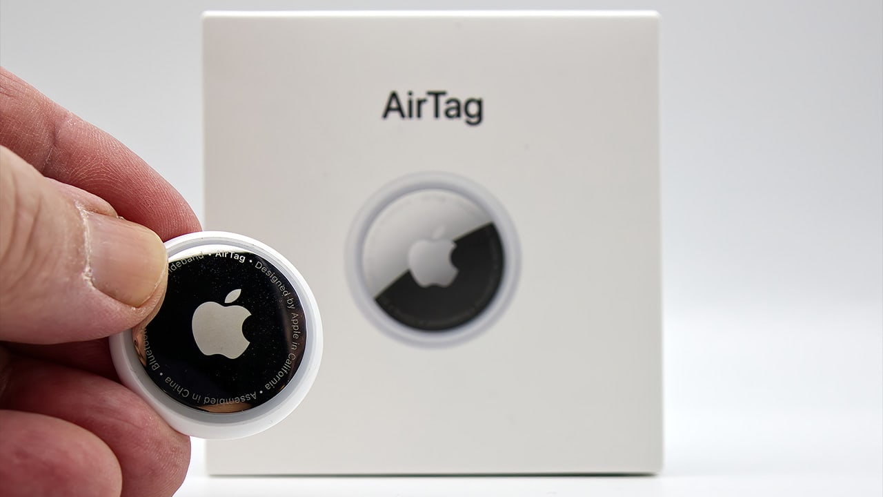 Image: Person holding AirTag in front of AirTag box.