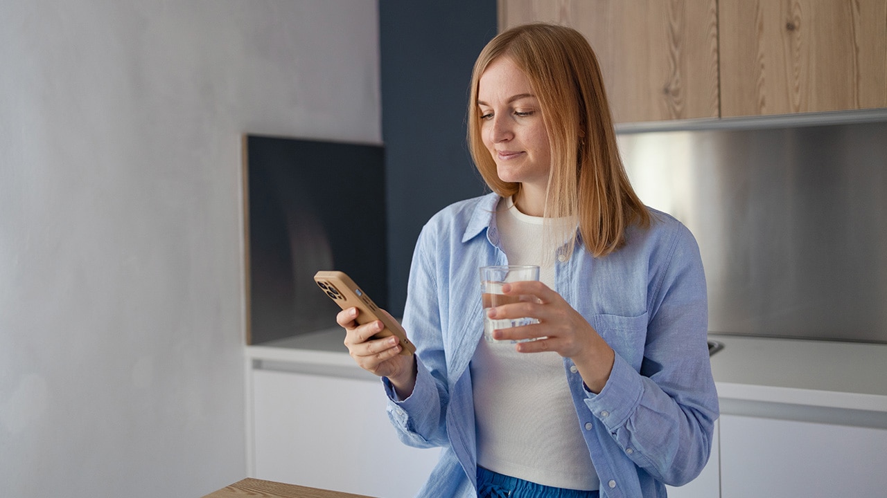 Image: Woman using iPhone in kitchen.